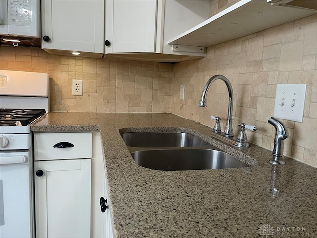 kitchen with sink, white cabinetry, stone counters, white appliances, and backsplash