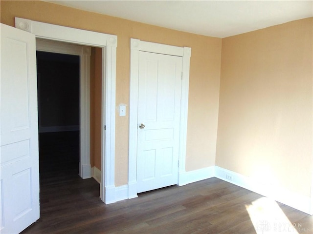 unfurnished bedroom with dark wood-type flooring and a closet