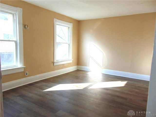 spare room with a wealth of natural light and dark hardwood / wood-style floors