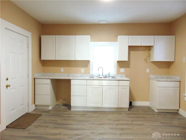 kitchen with sink, light wood-type flooring, and white cabinets