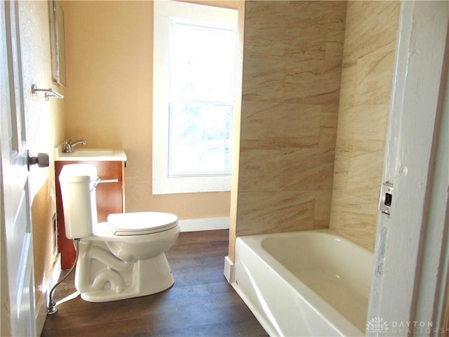 bathroom with wood-type flooring, a washtub, toilet, and sink