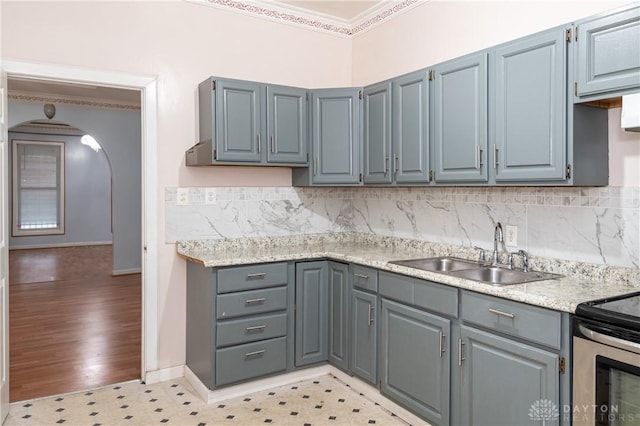 kitchen featuring stainless steel range, sink, ornamental molding, backsplash, and light wood-type flooring