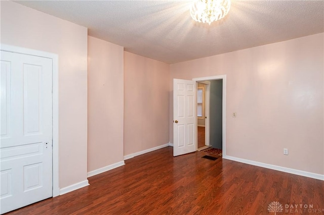 spare room featuring a textured ceiling and dark hardwood / wood-style flooring