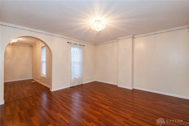 empty room featuring dark hardwood / wood-style flooring, a textured ceiling, and ornamental molding