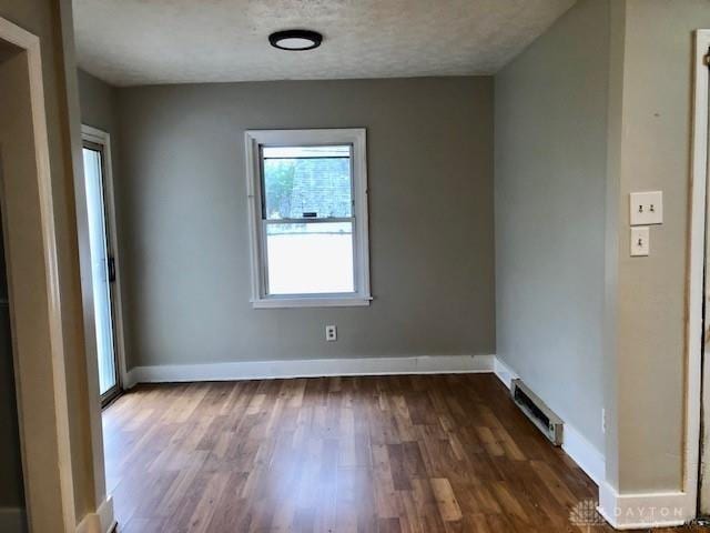 spare room featuring a textured ceiling and dark hardwood / wood-style floors