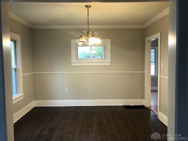 unfurnished dining area featuring dark hardwood / wood-style flooring, ornamental molding, and a notable chandelier