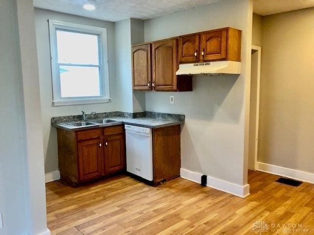 kitchen with white dishwasher, a textured ceiling, sink, and light hardwood / wood-style flooring