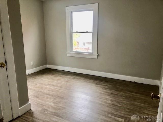 unfurnished room with dark wood-type flooring