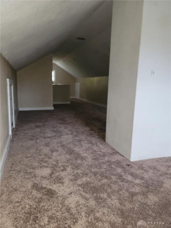 additional living space with lofted ceiling and dark colored carpet