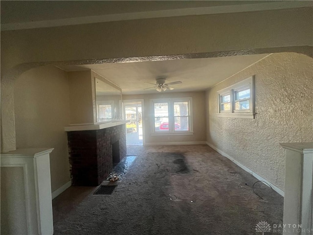 unfurnished living room with a fireplace, ceiling fan, and carpet flooring