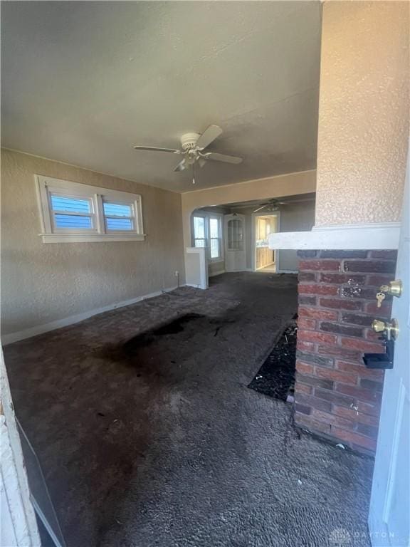 unfurnished living room featuring carpet flooring and ceiling fan