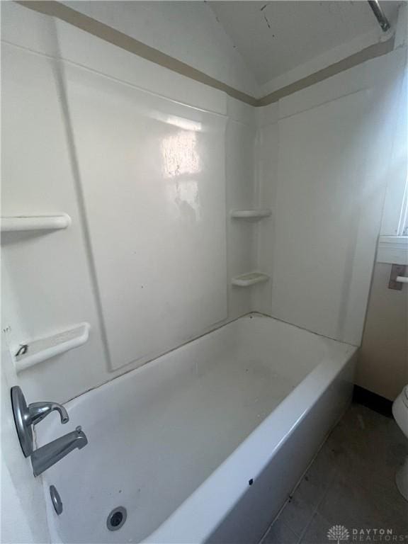 bathroom with bathtub / shower combination, toilet, and vaulted ceiling