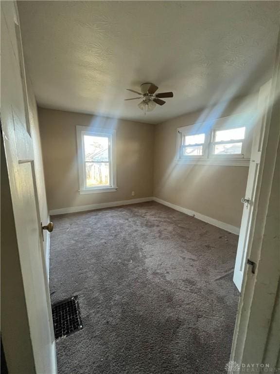 carpeted spare room featuring ceiling fan and a textured ceiling