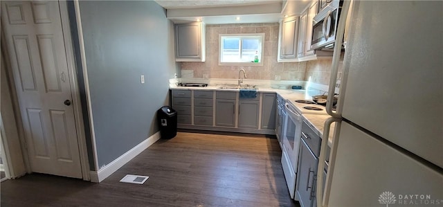 kitchen with backsplash, gray cabinetry, white appliances, sink, and dark hardwood / wood-style floors