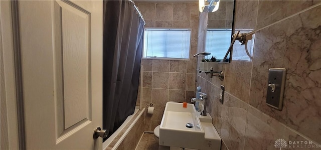 bathroom featuring shower / tub combo, tile walls, and sink