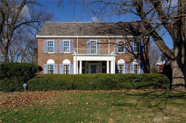 colonial inspired home with a balcony and a front lawn