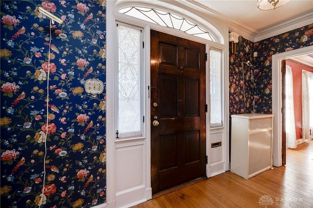 foyer entrance with crown molding and light hardwood / wood-style floors