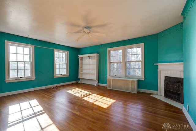 unfurnished living room featuring hardwood / wood-style flooring, plenty of natural light, radiator heating unit, and a tiled fireplace