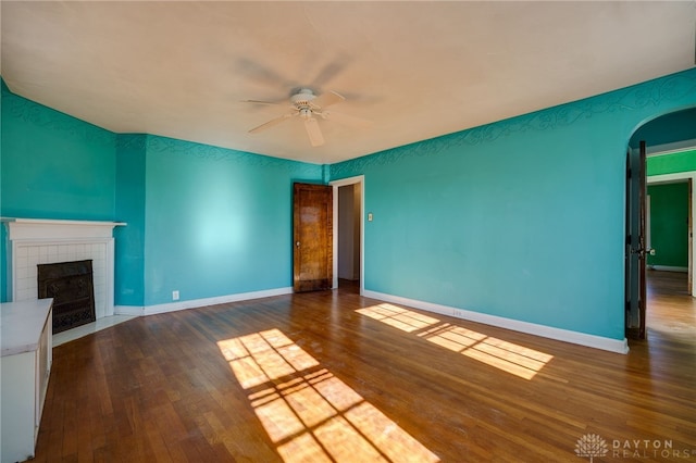 unfurnished living room featuring ceiling fan, a fireplace, and dark hardwood / wood-style floors