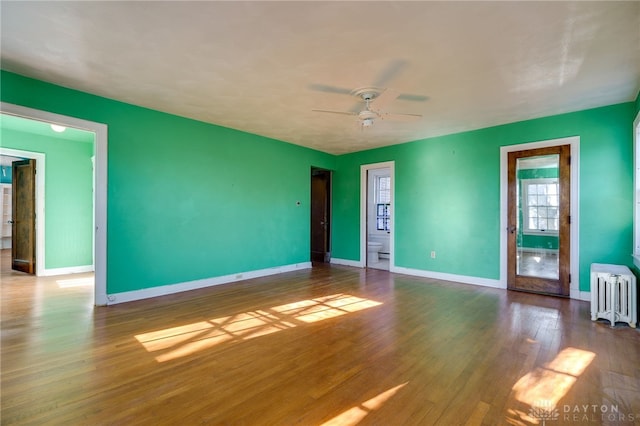 empty room featuring radiator heating unit, ceiling fan, and wood-type flooring