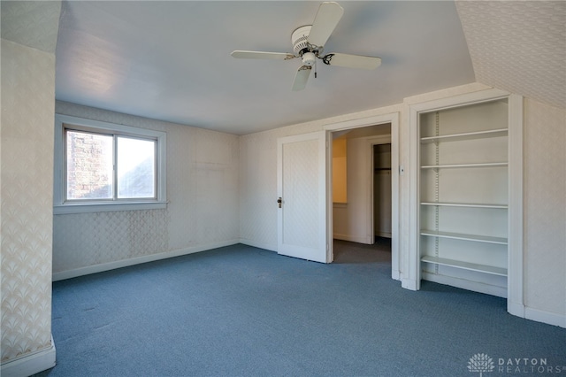 unfurnished bedroom featuring ceiling fan, dark carpet, and lofted ceiling