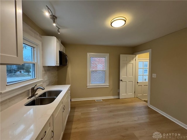 kitchen with white cabinets, light hardwood / wood-style floors, a healthy amount of sunlight, and sink