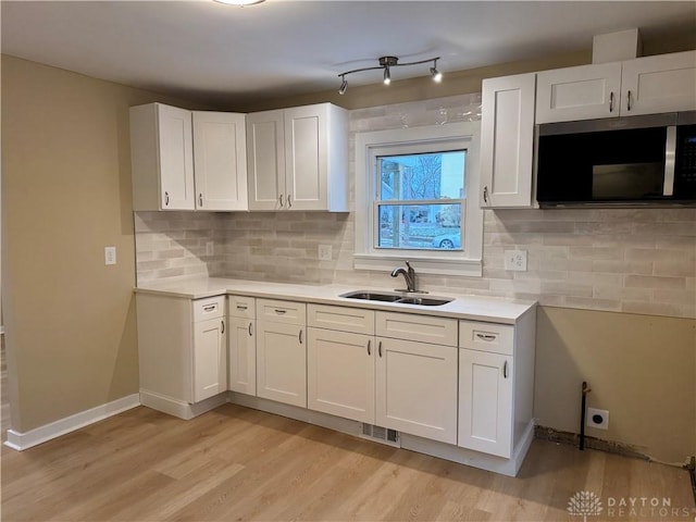 kitchen featuring white cabinets, light wood-type flooring, sink, and tasteful backsplash