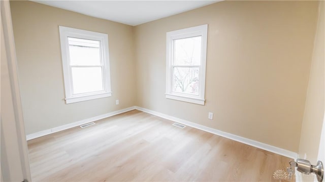 spare room with a wealth of natural light and light wood-type flooring