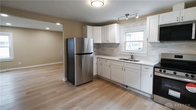 kitchen featuring appliances with stainless steel finishes, sink, white cabinets, and decorative backsplash