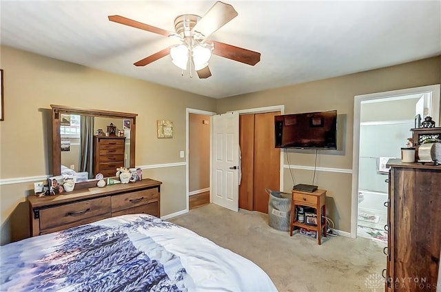 bedroom with light carpet, connected bathroom, and ceiling fan