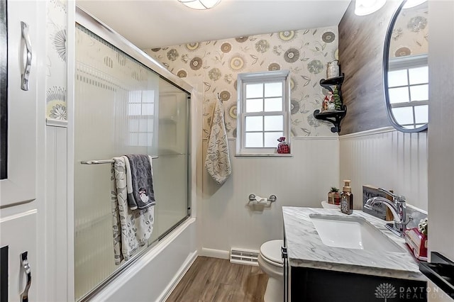 full bathroom with shower / bath combination with glass door, hardwood / wood-style floors, vanity, and toilet