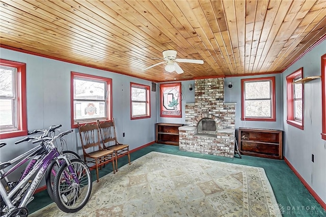 living area featuring a healthy amount of sunlight, wood ceiling, and a brick fireplace