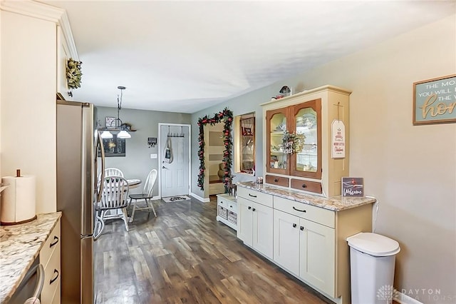 kitchen featuring white cabinets, stainless steel fridge, light stone countertops, decorative light fixtures, and dark hardwood / wood-style flooring