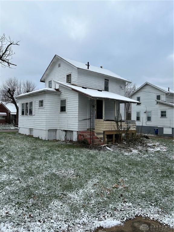 snow covered rear of property with a lawn