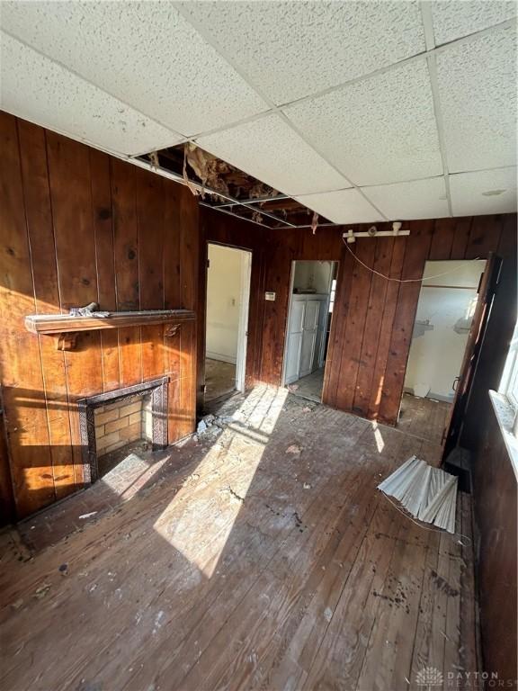 interior space with wood-type flooring, a paneled ceiling, and wooden walls