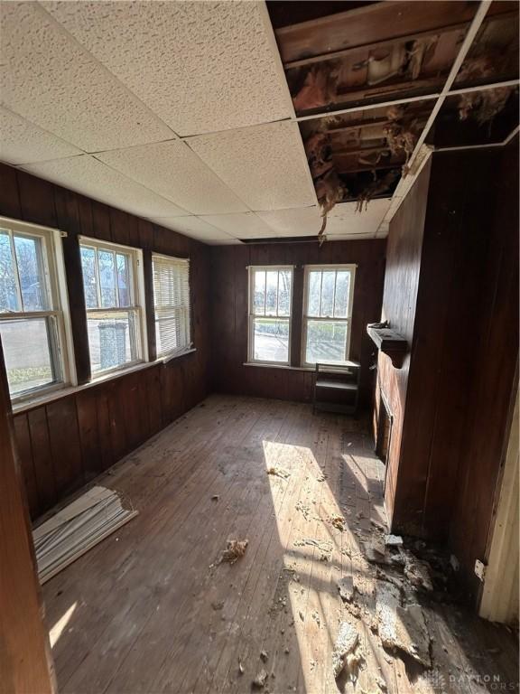 misc room featuring hardwood / wood-style floors, a paneled ceiling, and wooden walls