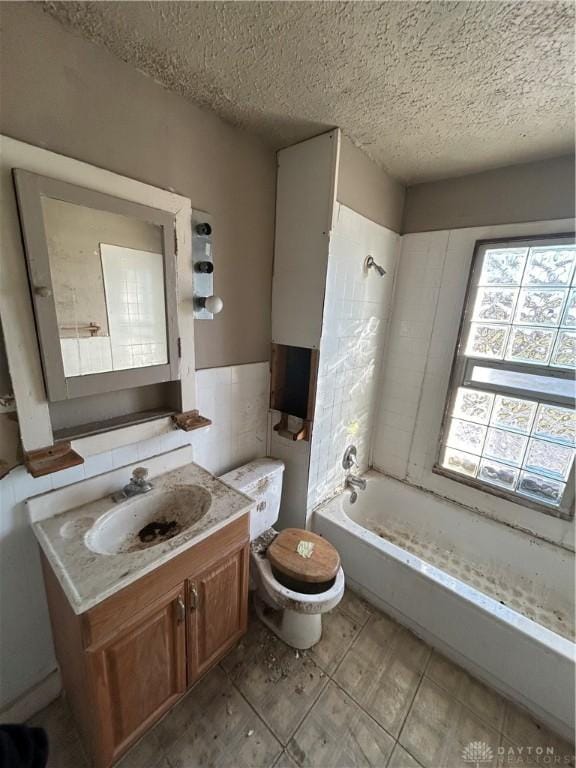 full bathroom featuring tiled shower / bath combo, tile patterned floors, a textured ceiling, toilet, and vanity