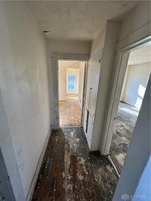 corridor featuring a textured ceiling and dark wood-type flooring