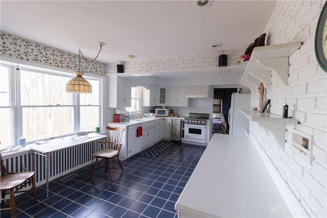 kitchen featuring white appliances, white cabinets, sink, dark tile patterned floors, and decorative light fixtures