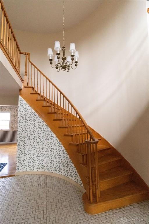 stairs featuring hardwood / wood-style flooring and a notable chandelier