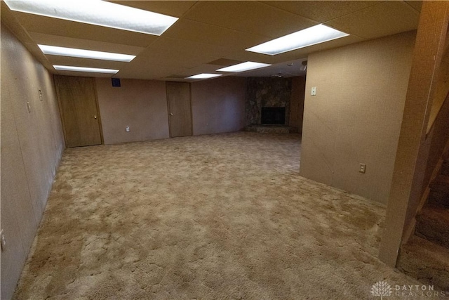 basement with a paneled ceiling, light carpet, and a fireplace