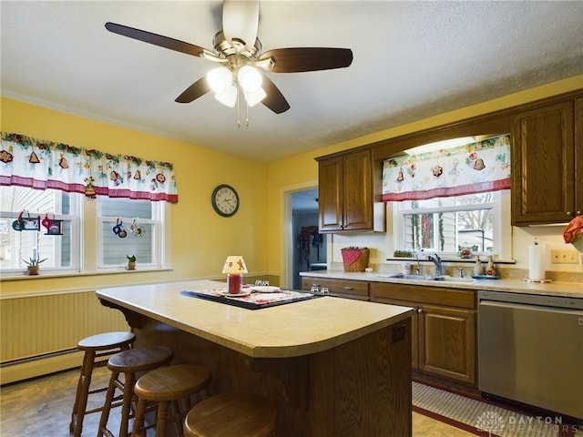 kitchen featuring ceiling fan, sink, stainless steel dishwasher, a breakfast bar area, and a kitchen island