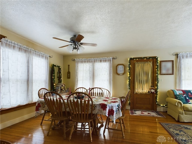 dining space with wood-type flooring, a textured ceiling, ceiling fan, and a baseboard heating unit