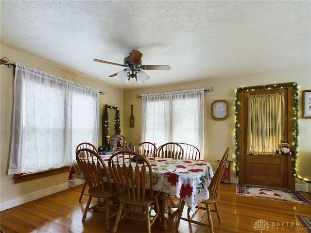 dining area featuring ceiling fan, wood-type flooring, and a textured ceiling