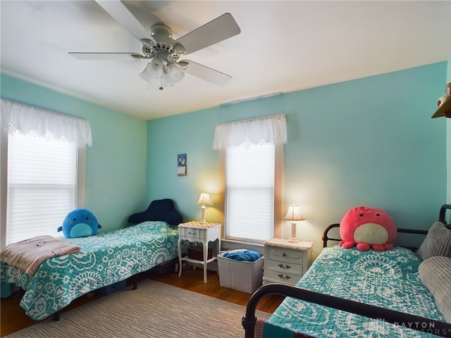 bedroom featuring hardwood / wood-style flooring, ceiling fan, and multiple windows