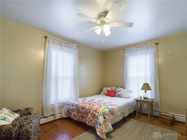 bedroom with dark hardwood / wood-style flooring, baseboard heating, and ceiling fan