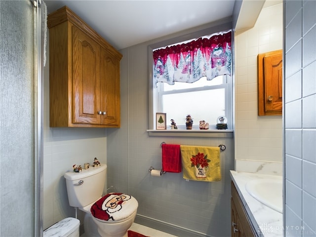 bathroom featuring vanity, toilet, and tile walls