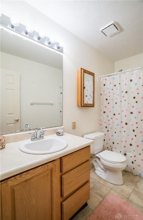 full bathroom with tile patterned floors, shower / tub combo with curtain, vanity, and toilet