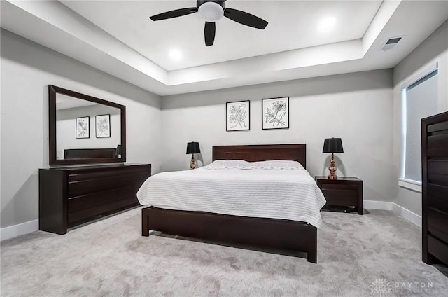 carpeted bedroom with ceiling fan and a raised ceiling