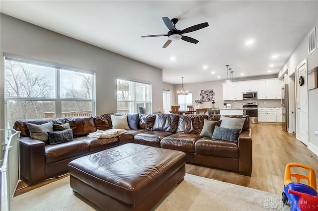 living room with light wood-type flooring and ceiling fan